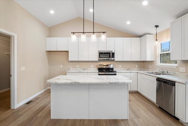 kitchen with appliances with stainless steel finishes, a center island, light wood-style floors, and a sink