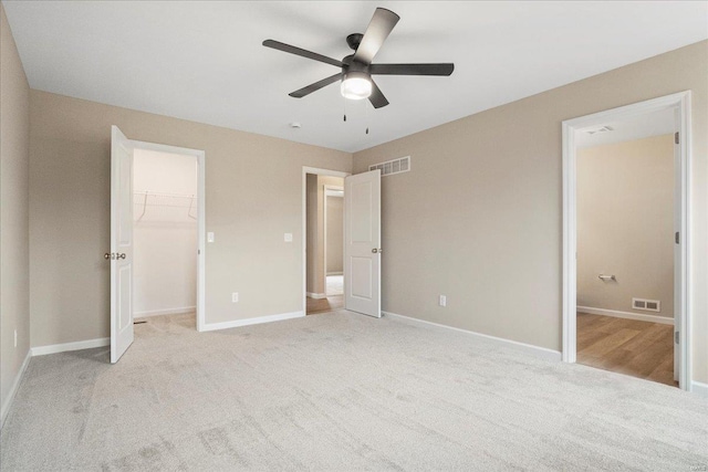 unfurnished bedroom with baseboards, a spacious closet, visible vents, and light colored carpet