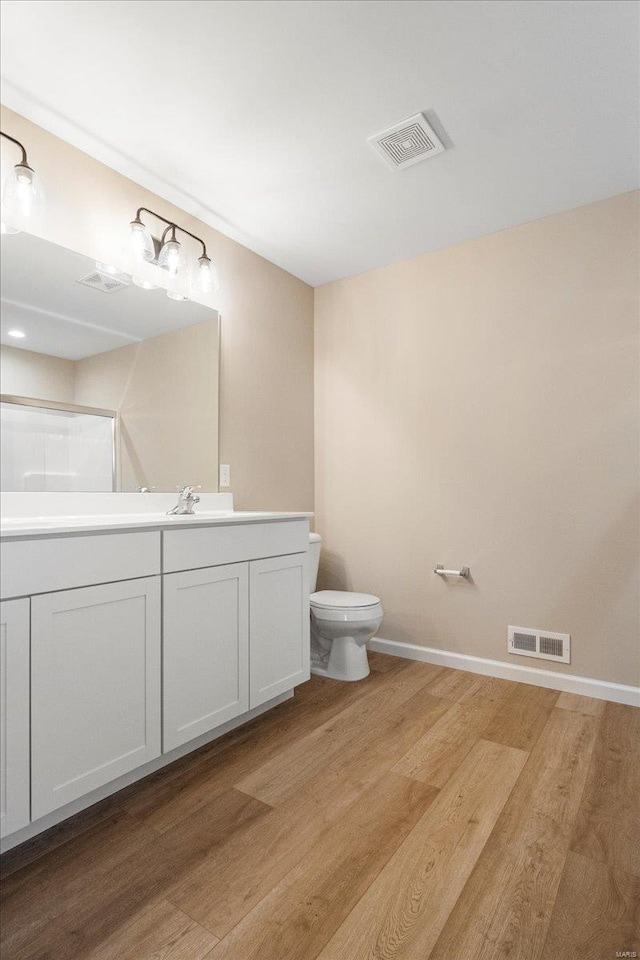bathroom with toilet, wood finished floors, visible vents, and baseboards