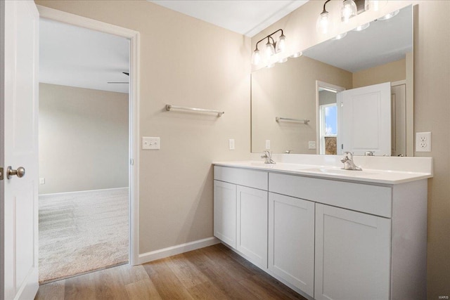 full bathroom featuring double vanity, baseboards, a sink, and wood finished floors