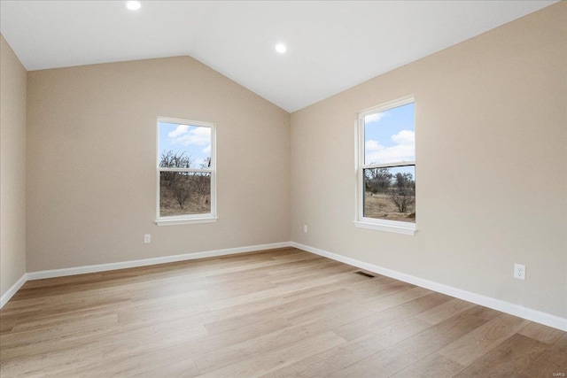 empty room with lofted ceiling, light wood-style flooring, visible vents, and a healthy amount of sunlight