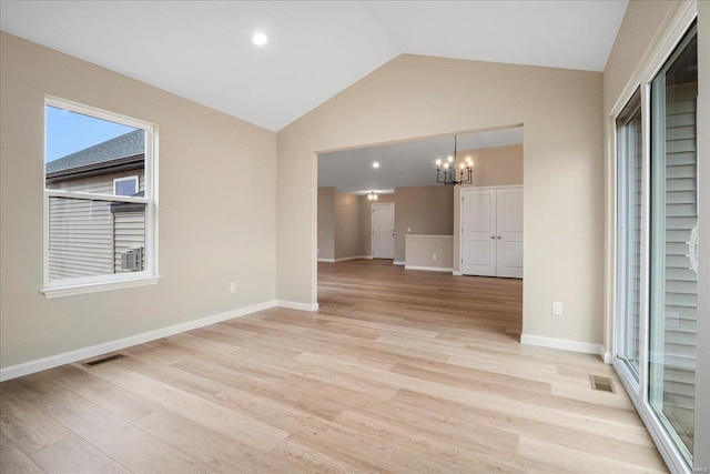 empty room featuring vaulted ceiling, light wood finished floors, and visible vents