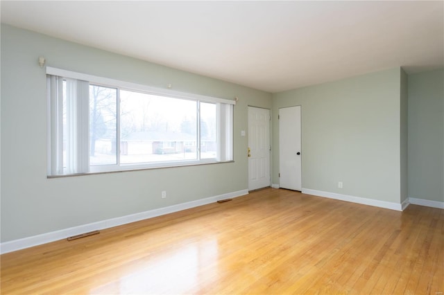 empty room featuring visible vents, baseboards, and light wood finished floors