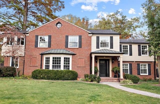 view of front of property with a standing seam roof, brick siding, metal roof, and a front lawn