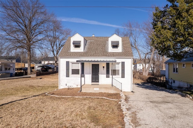 view of front of house featuring brick siding, roof with shingles, and a front yard