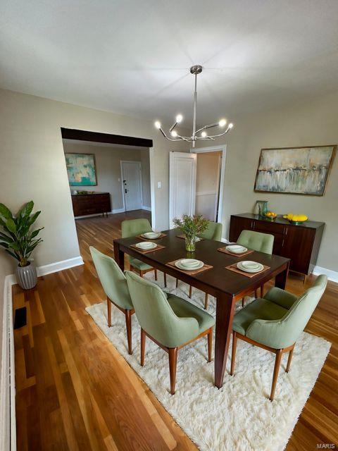 dining space featuring a chandelier, baseboards, and wood finished floors