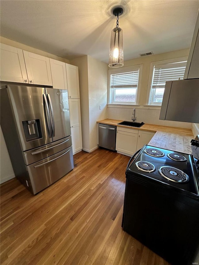 kitchen featuring stainless steel appliances, visible vents, white cabinets, a sink, and light wood-type flooring