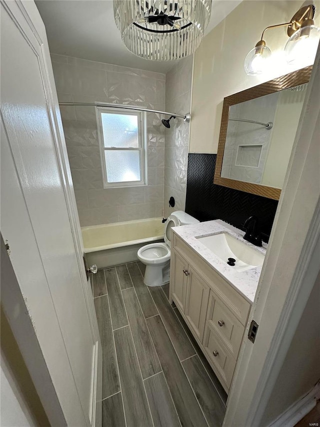 bathroom featuring toilet, vanity, washtub / shower combination, wood finish floors, and tile walls