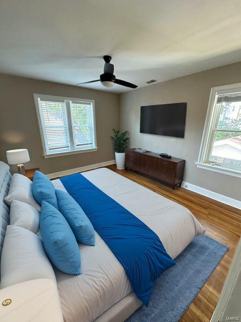 bedroom with wood finished floors, visible vents, and baseboards