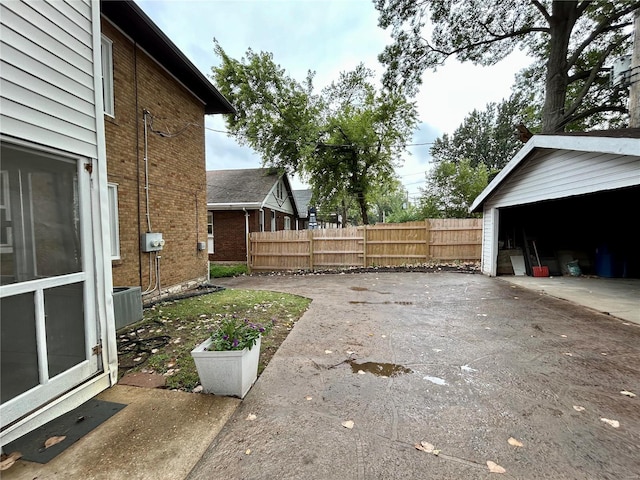 view of yard with an outbuilding, central AC unit, fence, and a garage