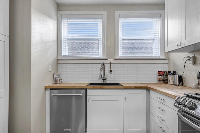 kitchen featuring stainless steel appliances, backsplash, a sink, and wood counters