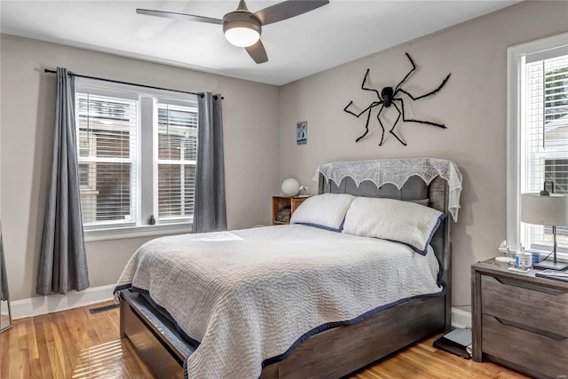 bedroom featuring visible vents, ceiling fan, baseboards, and wood finished floors