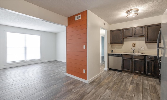 kitchen with dark brown cabinetry, stainless steel appliances, wood finished floors, a sink, and visible vents