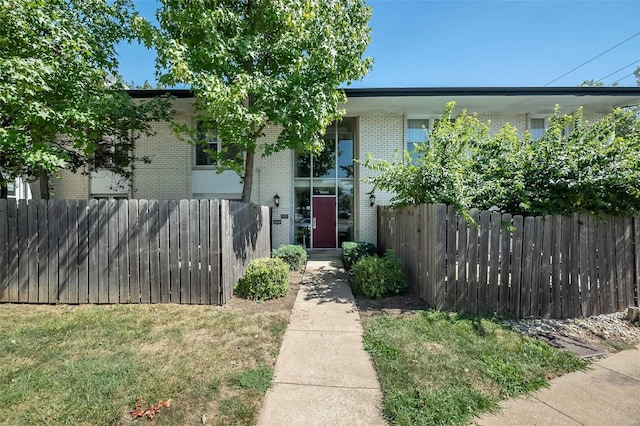 view of front of property featuring a front yard, brick siding, and fence