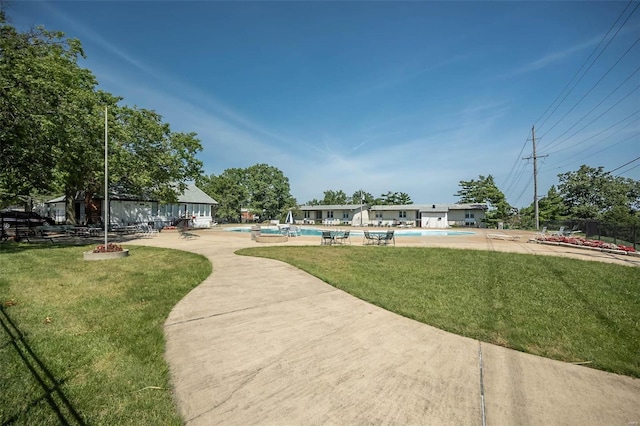 surrounding community with a pool, a lawn, fence, and a patio