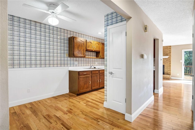 kitchen with a textured ceiling, light countertops, and brown cabinetry