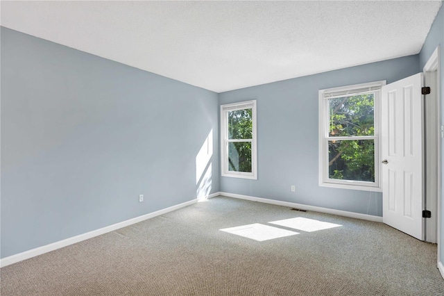 empty room with a healthy amount of sunlight, baseboards, and light colored carpet