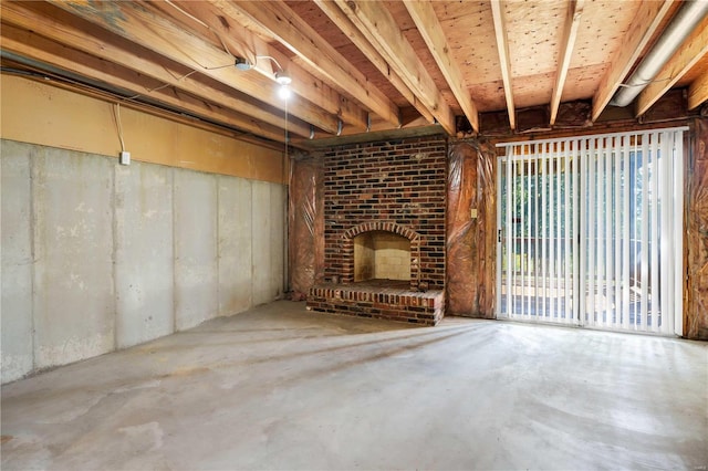 unfurnished living room with a brick fireplace and unfinished concrete floors