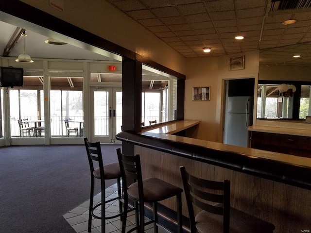 bar featuring a paneled ceiling, visible vents, freestanding refrigerator, carpet flooring, and a bar