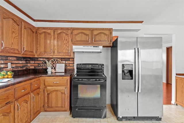 kitchen with under cabinet range hood, brown cabinets, black electric range oven, dark countertops, and stainless steel fridge