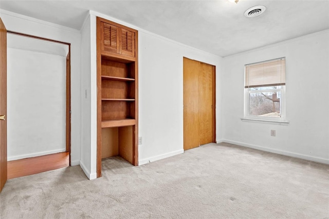 unfurnished bedroom featuring baseboards, visible vents, ornamental molding, carpet floors, and a closet