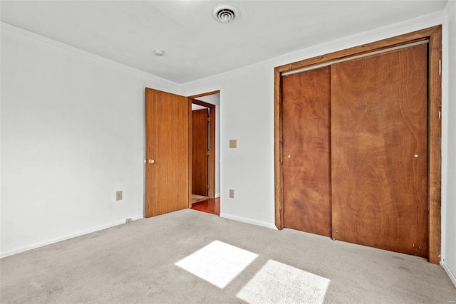 unfurnished bedroom featuring carpet, crown molding, a closet, visible vents, and baseboards