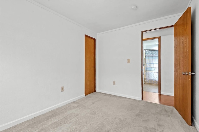 carpeted spare room with ornamental molding and baseboards