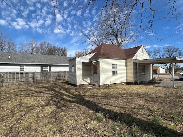 rear view of property with roof with shingles, entry steps, crawl space, fence, and a carport