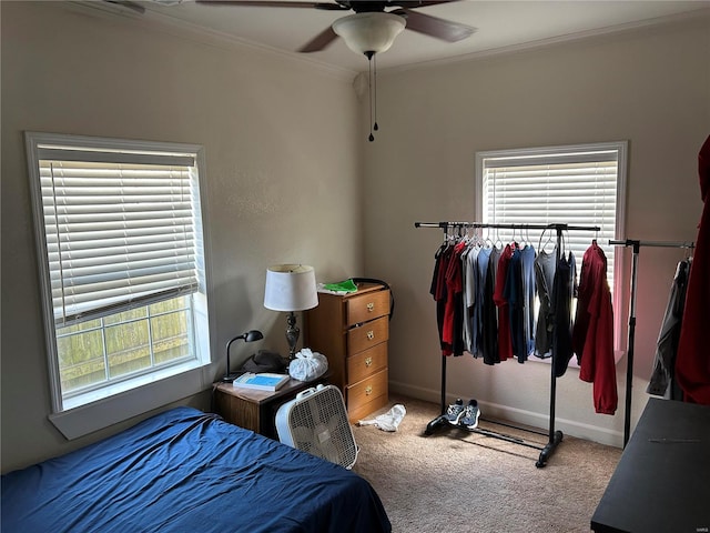 carpeted bedroom with ceiling fan, ornamental molding, and baseboards