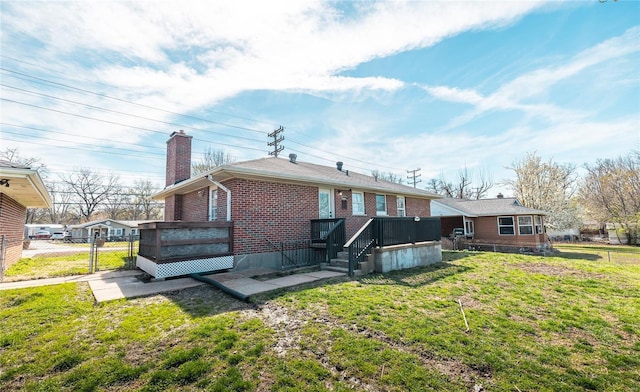 rear view of house featuring a gate, a chimney, fence, brick siding, and a lawn