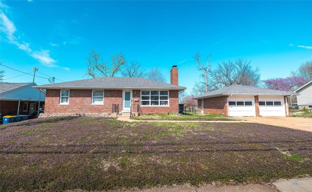 view of front of home featuring a chimney, brick siding, an outbuilding, and a garage