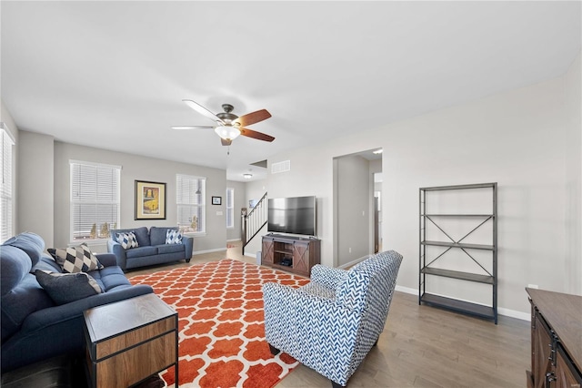 living room featuring stairs, wood finished floors, visible vents, and baseboards