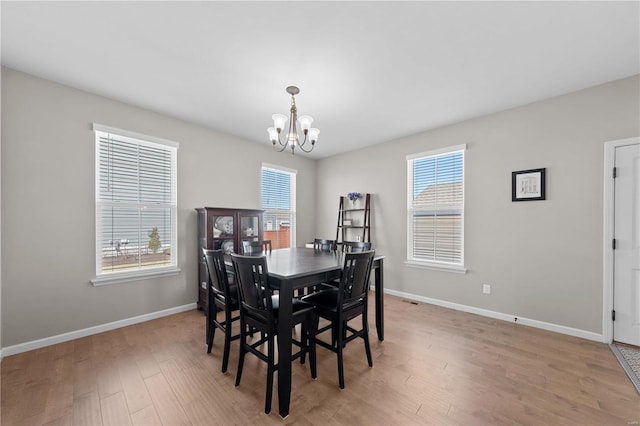 dining space with a notable chandelier, light wood-style flooring, and baseboards