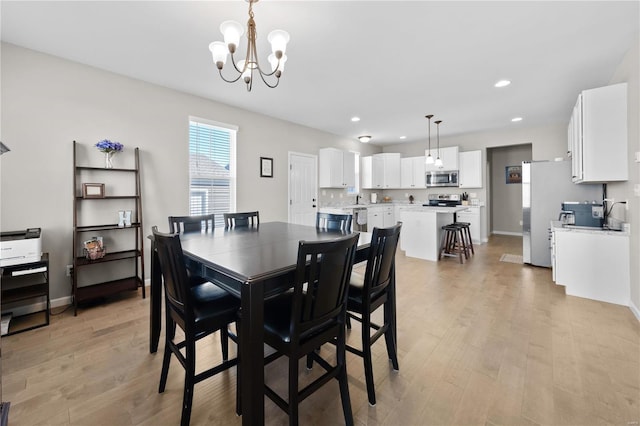 dining area with light wood finished floors, baseboards, a notable chandelier, and recessed lighting