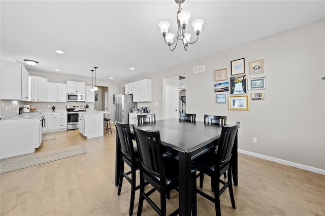 dining room with baseboards, visible vents, stairway, light wood-style floors, and a notable chandelier