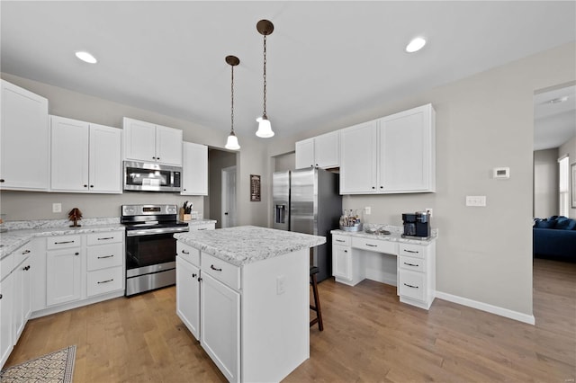 kitchen featuring a center island, a breakfast bar, stainless steel appliances, light wood-style floors, and white cabinets