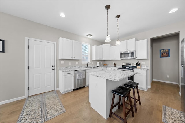 kitchen featuring a breakfast bar area, light wood-style flooring, a sink, white cabinets, and appliances with stainless steel finishes