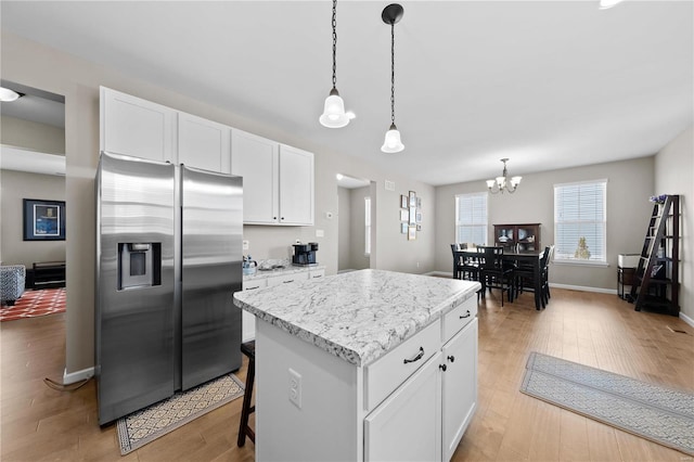 kitchen with light wood-type flooring, a kitchen island, white cabinetry, and stainless steel fridge with ice dispenser