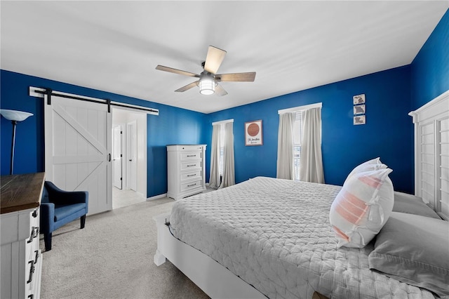 carpeted bedroom featuring a barn door and a ceiling fan