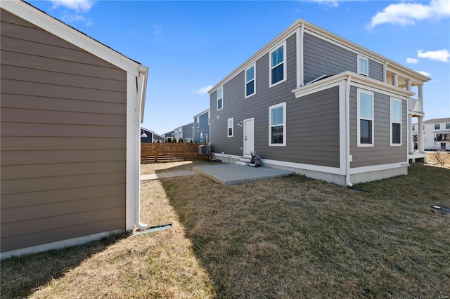 back of property with entry steps, a patio area, fence, and a lawn