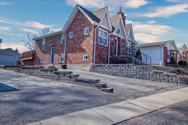 view of property exterior with brick siding, an outdoor structure, and a chimney