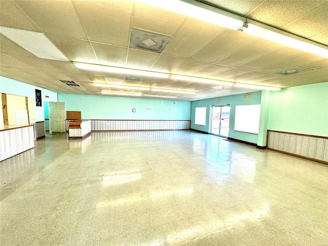 interior space featuring a wainscoted wall, visible vents, and baseboards