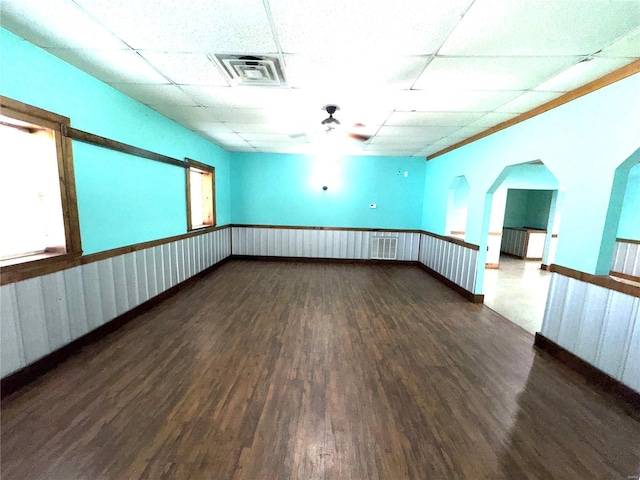 empty room featuring a drop ceiling, wood finished floors, and visible vents