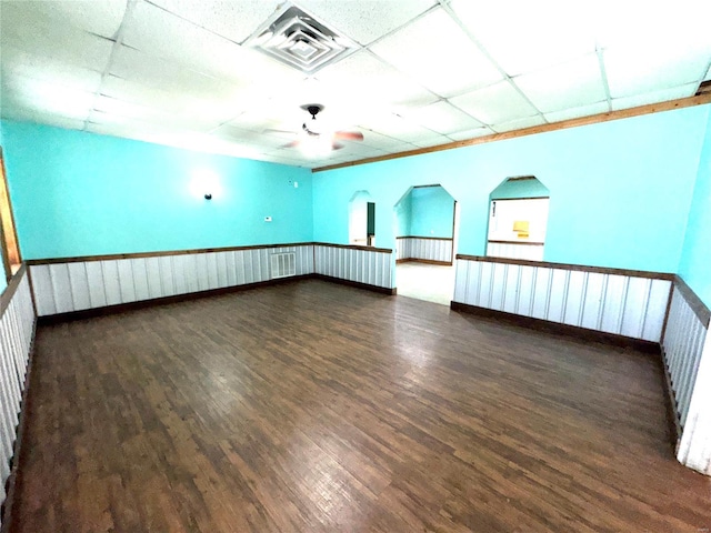 empty room featuring a paneled ceiling, a ceiling fan, visible vents, and wood finished floors