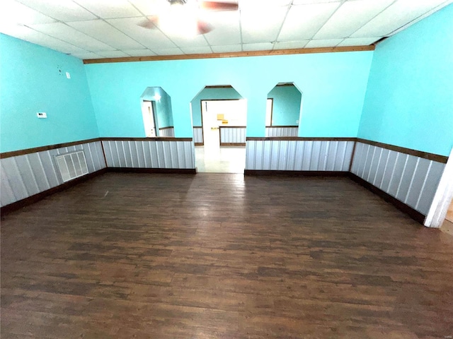 spare room featuring dark wood-type flooring, a drop ceiling, and visible vents