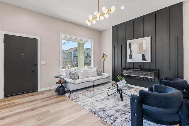 living room with a chandelier, recessed lighting, baseboards, and light wood finished floors