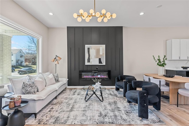 living room featuring a chandelier, recessed lighting, a large fireplace, and light wood-style flooring