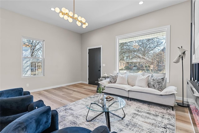 living area with a chandelier, light wood-style flooring, and a healthy amount of sunlight