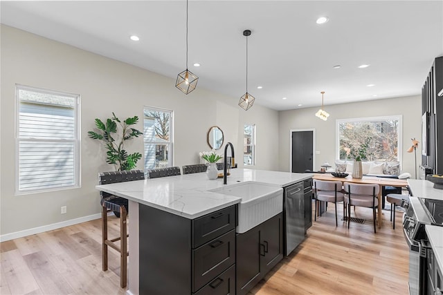 kitchen with electric stove, dishwashing machine, a breakfast bar, dark cabinetry, and a sink