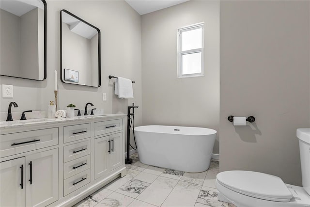 bathroom featuring a freestanding bath, marble finish floor, a sink, and toilet